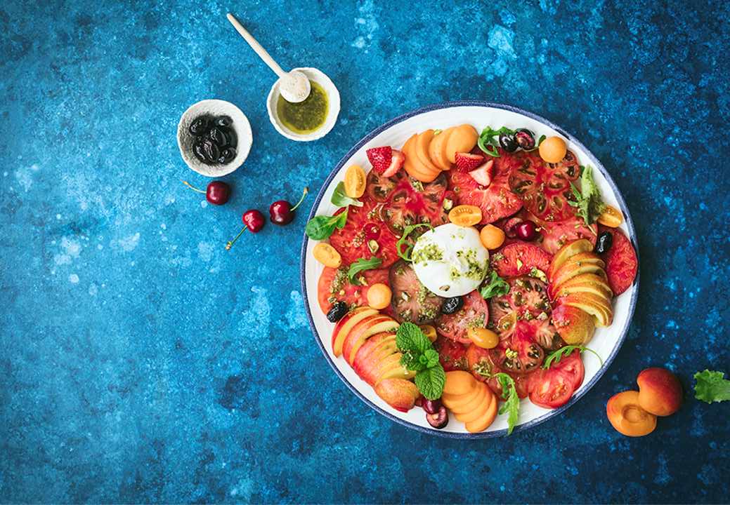 Ensalada de tomates, frutas de hueso, burrata con pesto